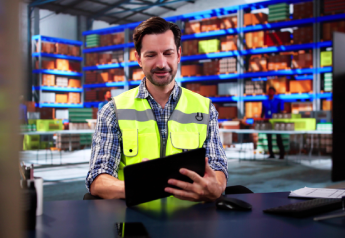 warehouse manager in safety vest reviewing supply chain data and ERP risk indicators on a tablet