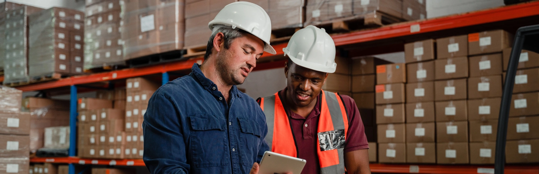 Two warehouse managers reviewing wms consulting implementation plan in a distribution facility